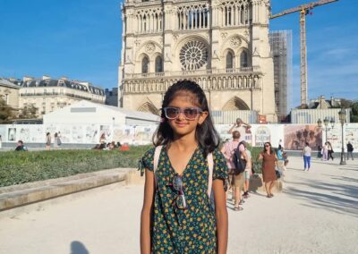 Riya standing in front of a temple. She is smiling and wearing sunglasses