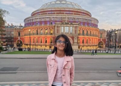 Riya wearing a pink denim jacket, smiles in front of