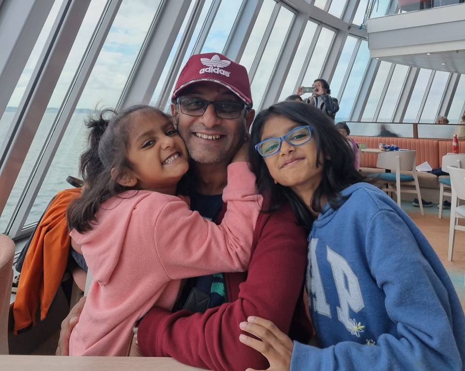 Riya is wearing blue eye glasses and smiling at the camera